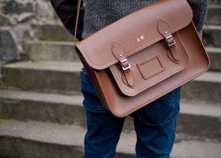 person carrying brown leather shoulder bag