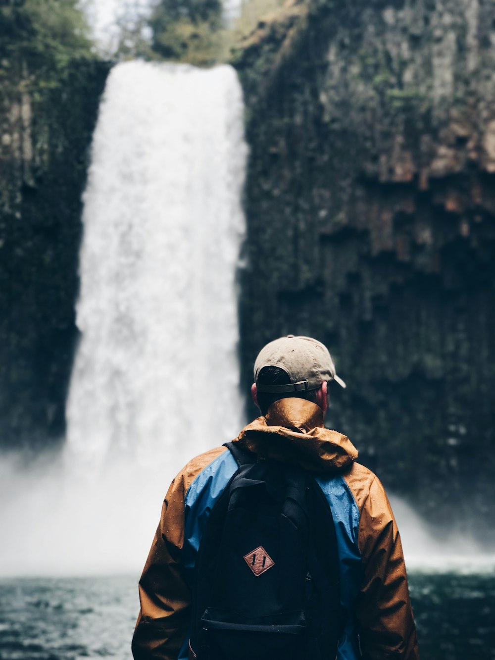 Selektive Fokusfotografie eines Mannes, der auf Wasserfällen steht