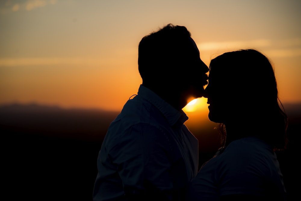silhouette of man kissing woman's forehead
