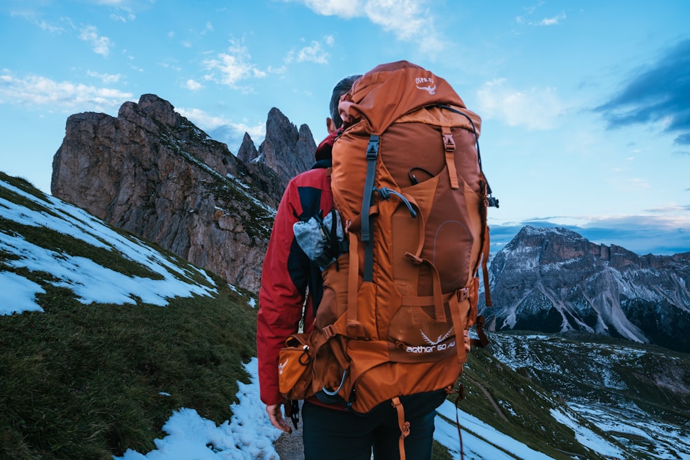 man carrying backpack standing on mountain during daytime