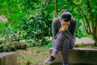 A person wearing the orukka word bracelet while walking in a sunlit park, earbuds in.