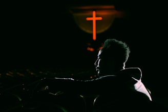 A warm, inviting scene of a person watching a sermon on a tablet with headphones on, surrounded by soft lighting.