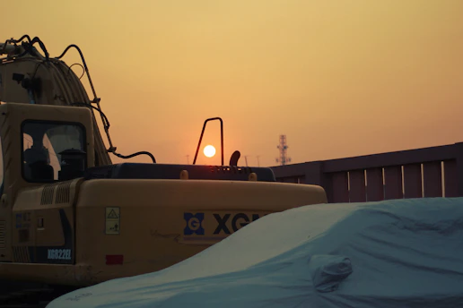 Mobile surveillance trailer stationed at a busy construction site during sunset.