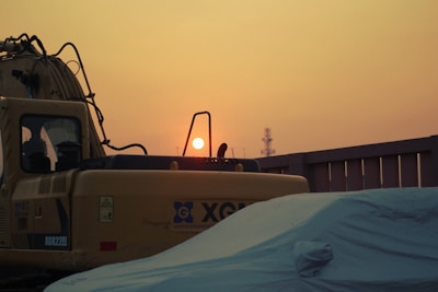Heavy machinery parked at a construction site during sunset.