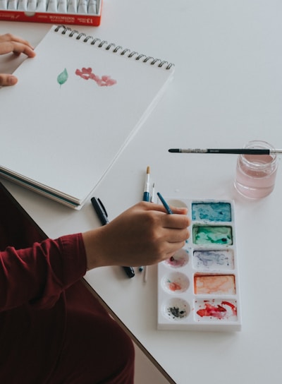 person dipping paintbrush on paint