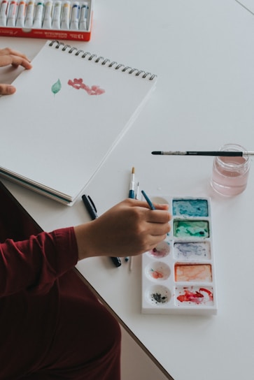 person dipping paintbrush on paint