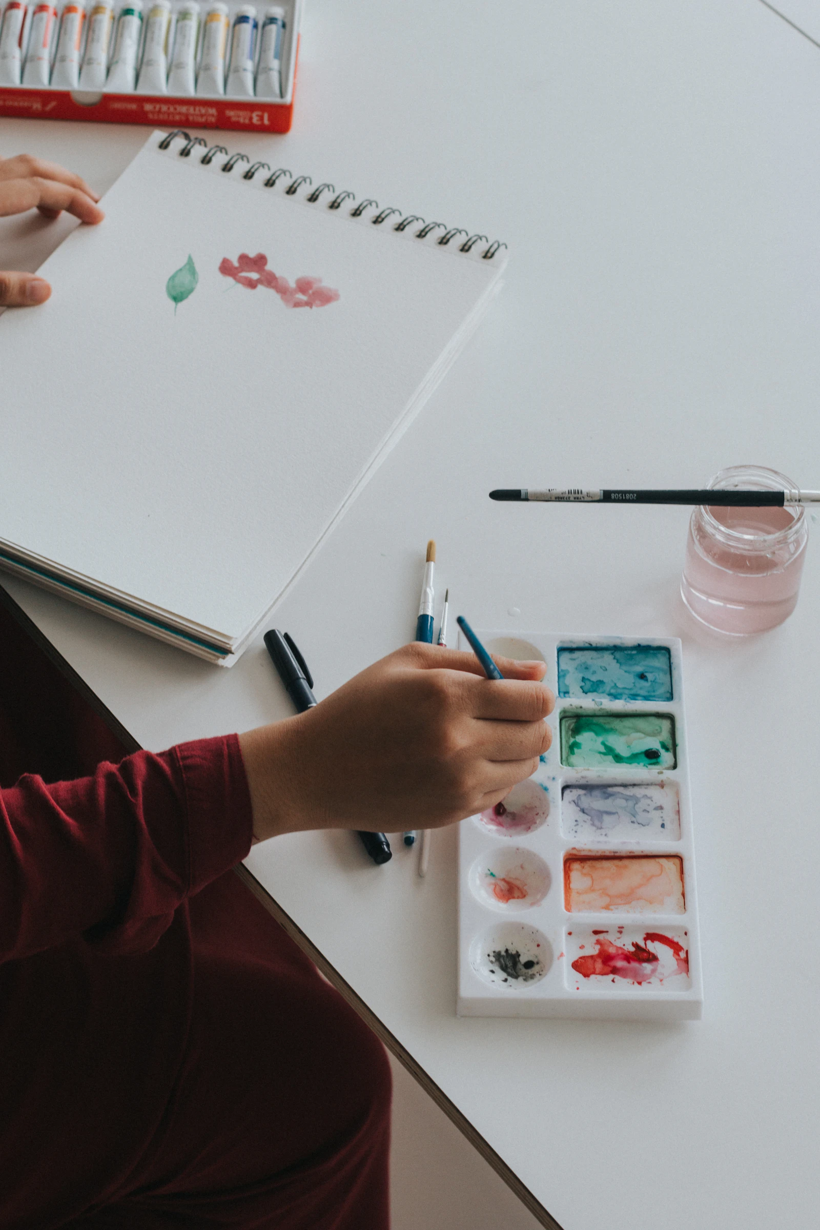 Palette d'aquarelle, pinceaux et carnet avec de délicates touches de couleur