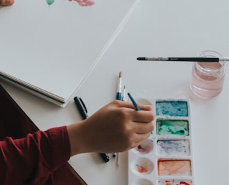 person dipping paintbrush on paint