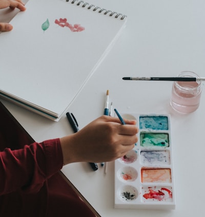 person dipping paintbrush on paint