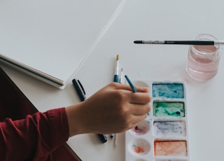 person dipping paintbrush on paint