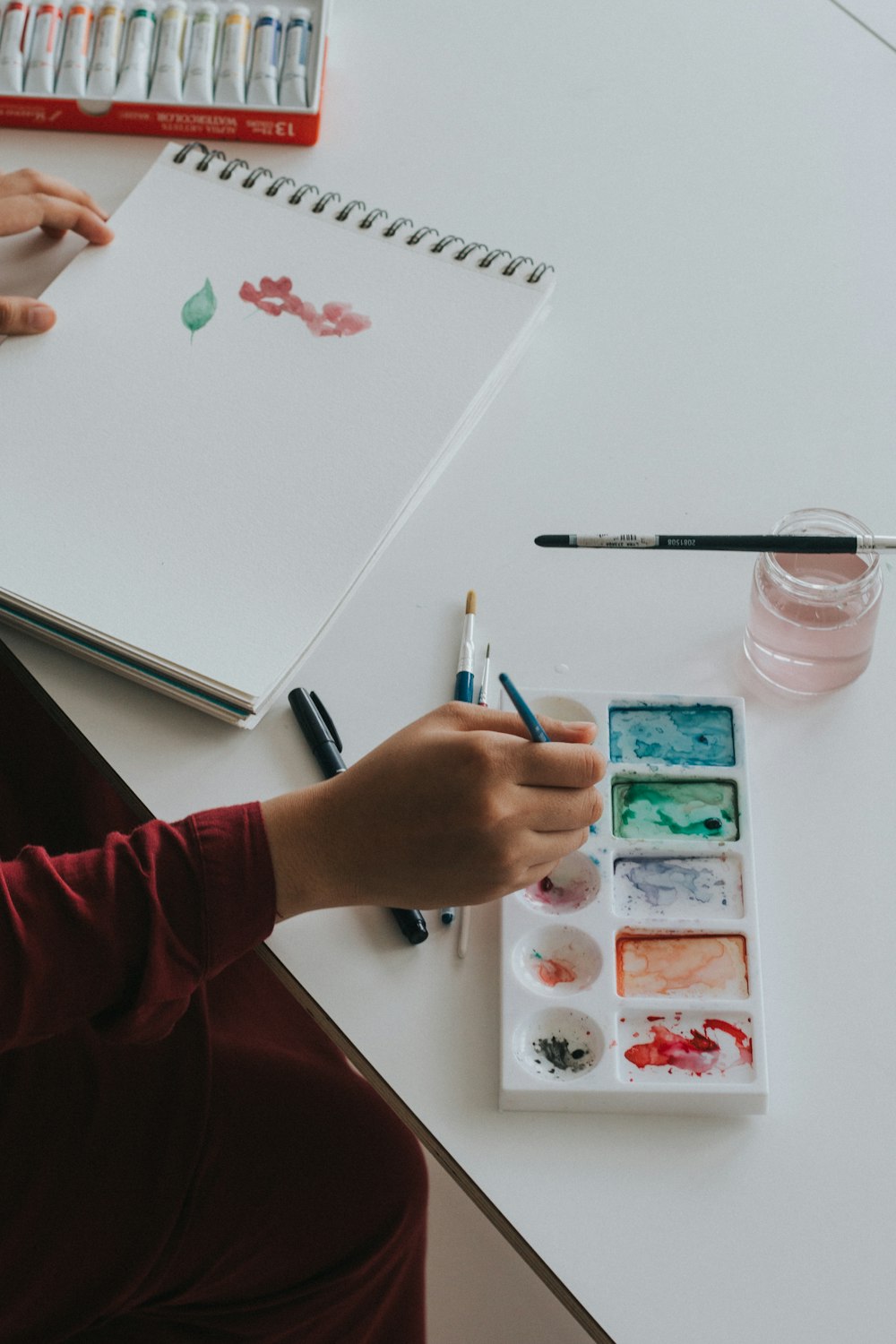 person dipping paintbrush on paint