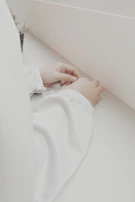 Close-up of a doctor gently examining a patient's hand in a bright, minimalist clinic space.