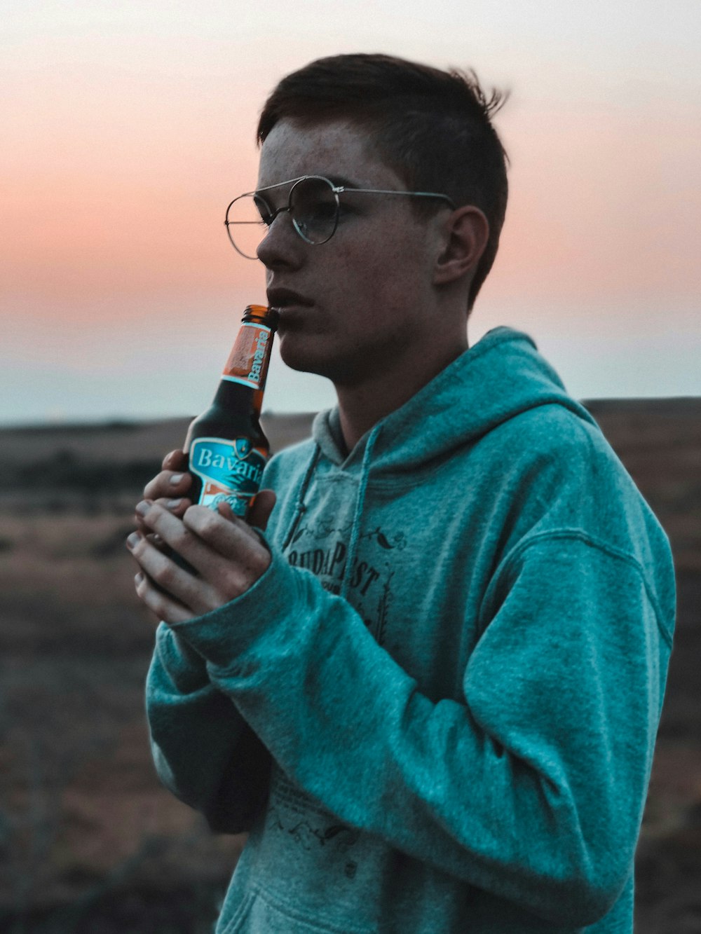 man wearing hoodie holding a bottle of beer