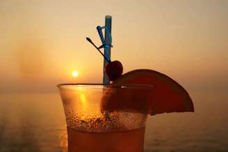 Close-up of a gold-rimmed cocktail glass with a sunset backdrop.