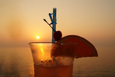 Sunset background with a glass of Geyra gin and tonic, ice cubes sparkling.