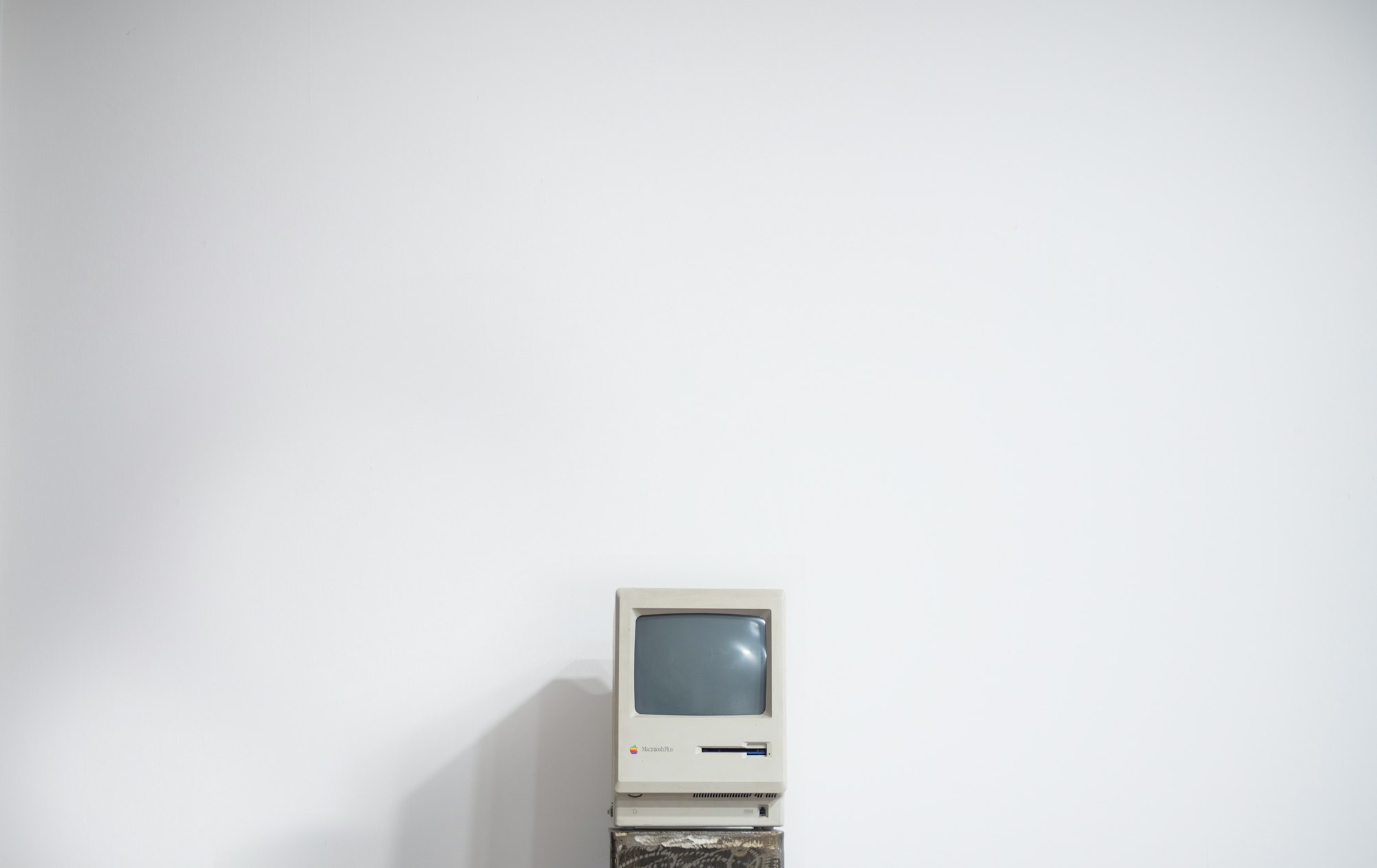 Old Macintosh computer sits alone on a white wall
