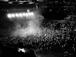 Wide shot of a packed venue with cinematic lighting and smoke effects creating an electric atmosphere.