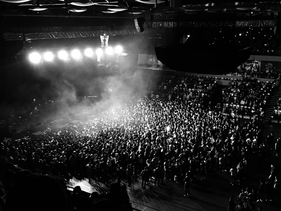 Wide shot of a packed venue with cinematic lighting and smoke effects creating an electric atmosphere.