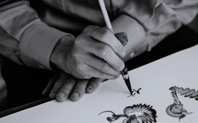 An artist painting intricate patterns on a vibrant fabric, captured with soft focus background.