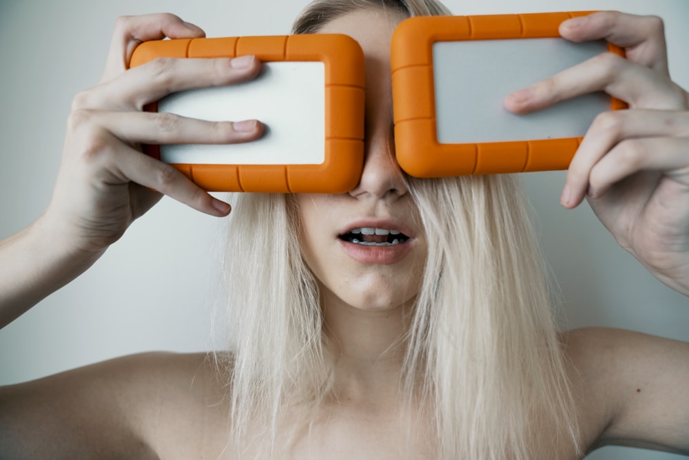 mulher segurando dois estojos de plástico branco e laranja