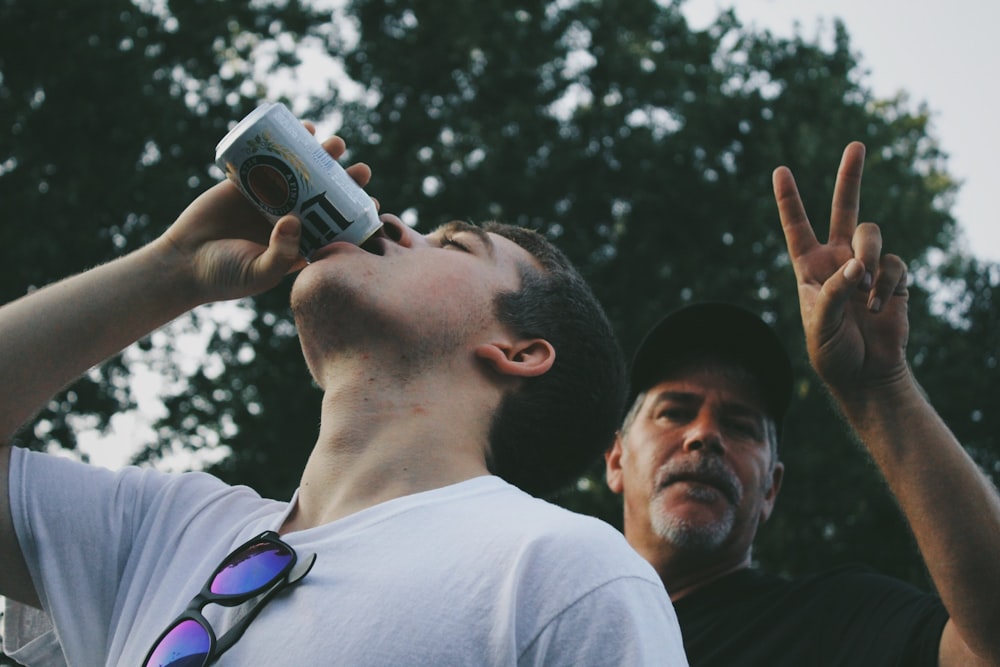 man drinking beer in can with man during daytime