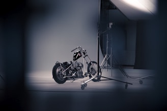 A shiny motorcycle parked in a studio with red, black, and white colors in the background.