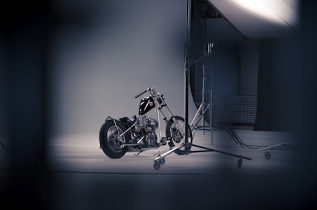A shiny motorcycle parked in a studio with red, black, and white colors in the background.