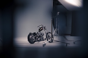 A motorcycle is positioned in a studio setting, surrounded by photo equipment such as stands and lighting. The environment appears professional, likely used for a photo shoot, with a focus on the motorcycle's sleek design and chrome detailing.