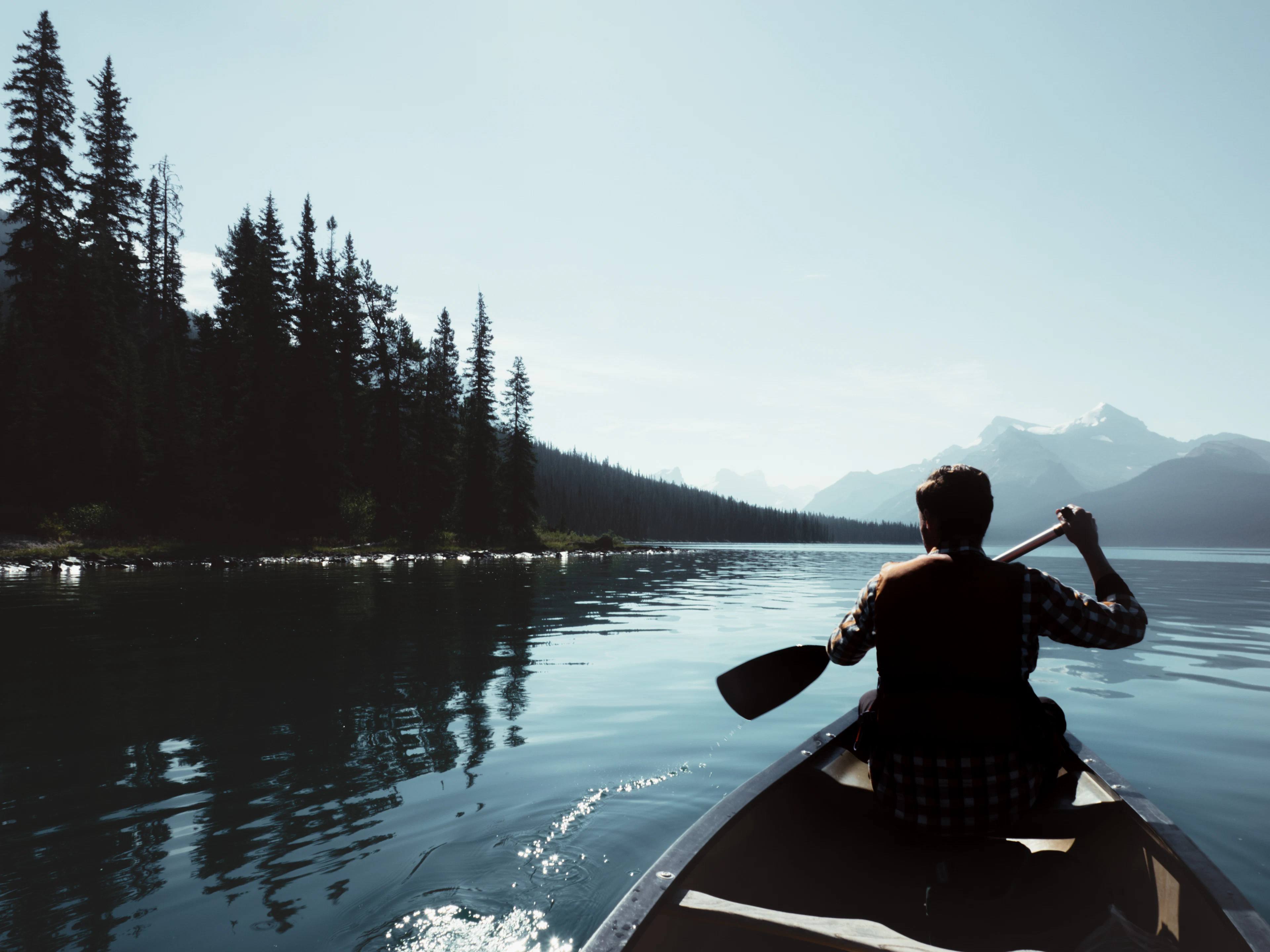 A paddler seen from behind in a canoe on calm Maligne Lake, Jasper National Park