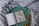 An open book with a simple, artistic illustration of a bird in the middle of one page, placed on a round, green tray. The text on the opposite page reads 'A little space to be creative'. Dried oak leaves are scattered on the tray, which rests on a softly wrinkled, grey fabric.