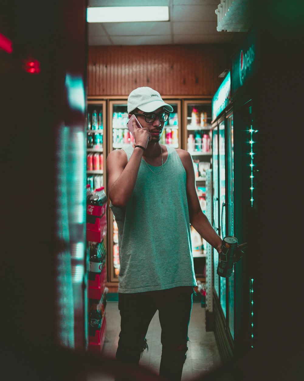 man using smartphone standing in front on beverage cooler inside store