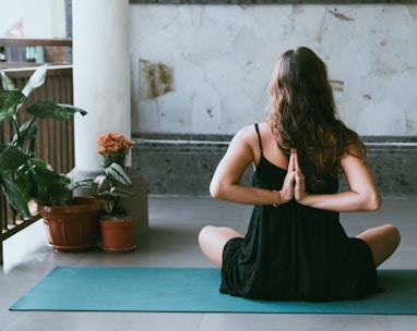 woman wearing black shirt sitting on green yoga mat