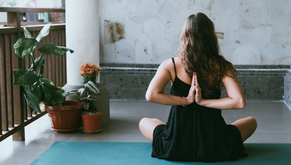 woman wearing black shirt sitting on green yoga mat