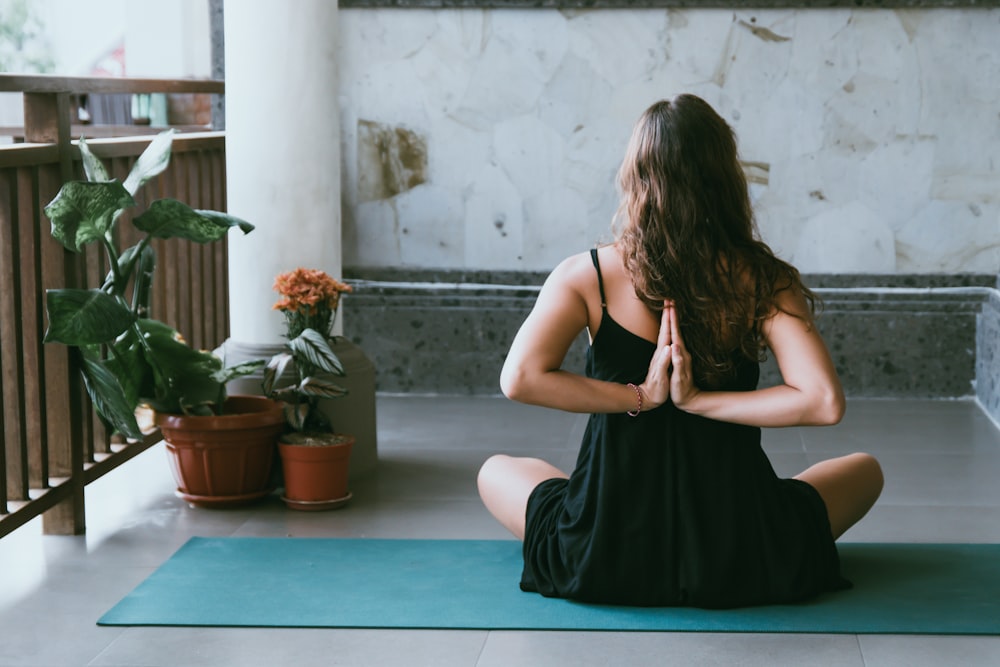 Frau trägt schwarzes Hemd und sitzt auf grüner Yogamatte