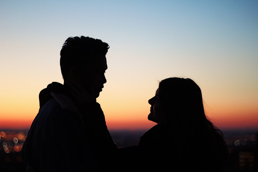 silhouette of man standing beside woman facing each other