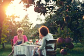 A multi-generational family gathered around a garden table, sharing stories and tasting honey.