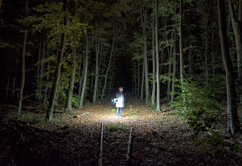 woman standing holding flashlight into woods