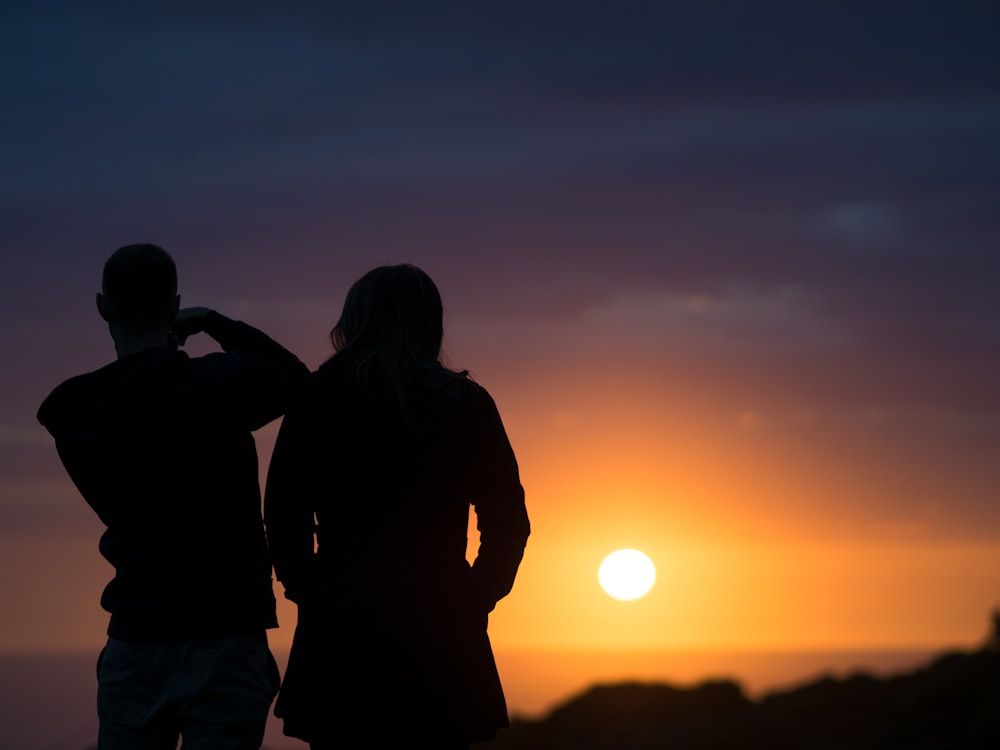 man and woman silhouettes during golden hour
