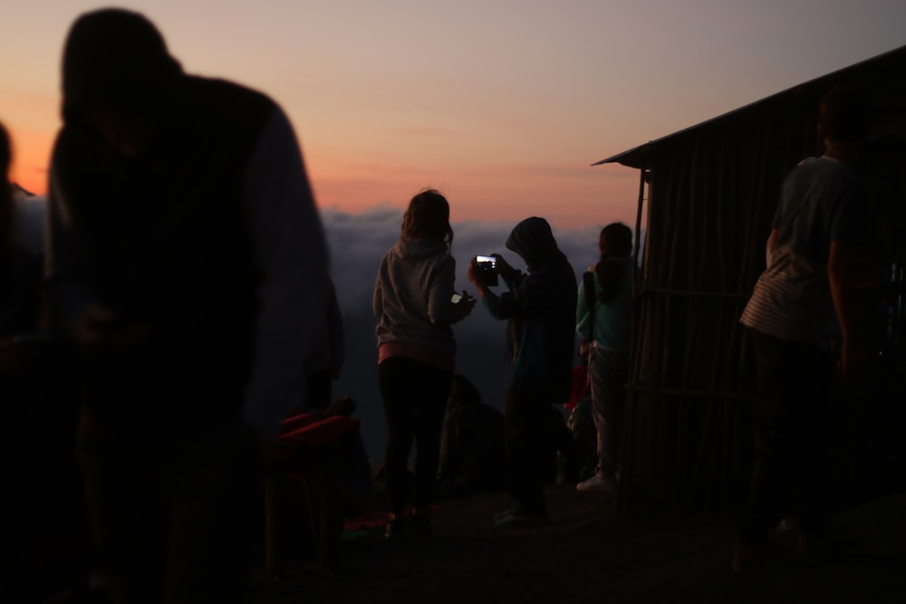 group of people near hut at sunset