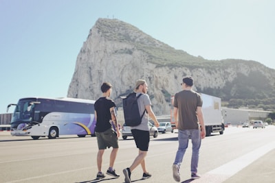 three men walking on street near vehicles during daytime