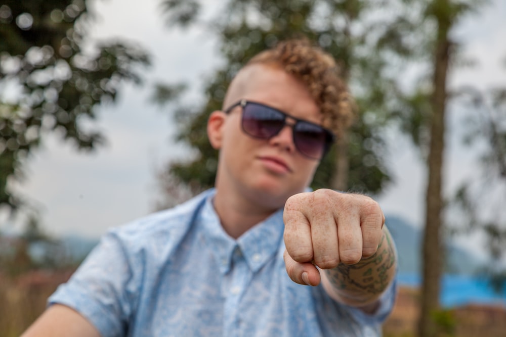 man wearing blue collar top with fist bump gesture