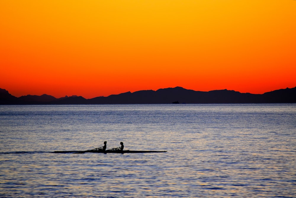 Silhouette von zwei Personen auf dem Boot während des Sonnenuntergangs