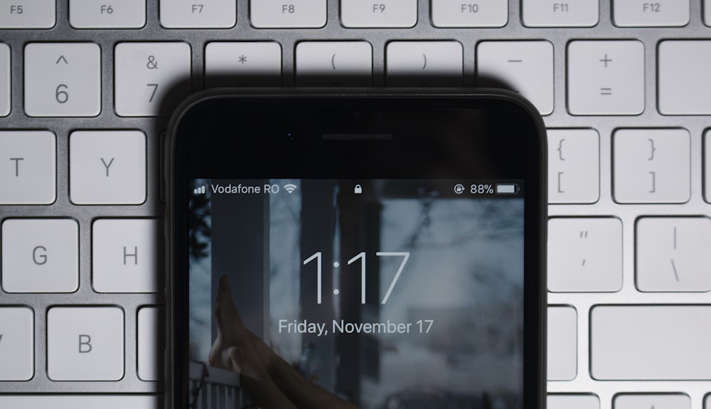 iPhone negro en el teclado de la computadora gris