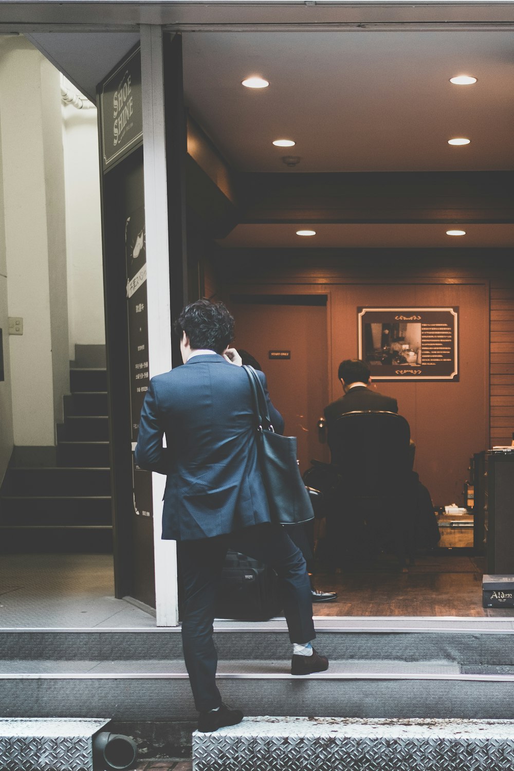 man in black suit standing on gray stairs