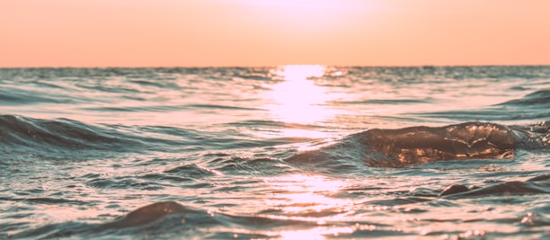 Sunset over calm ocean horizon with soft golden light.