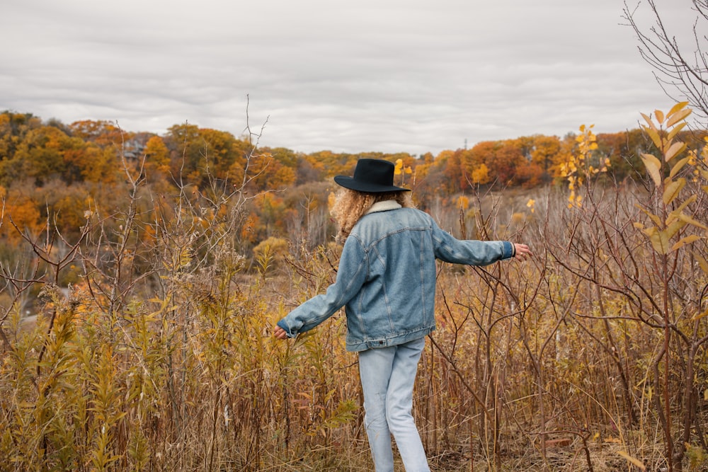 woman wearing blue jacket walking towards the brown grass