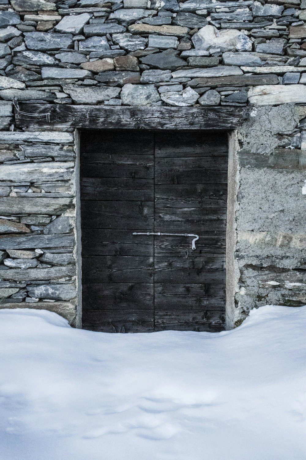 two black wooden doors behind snow