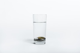 coins on clear drinking glass with water