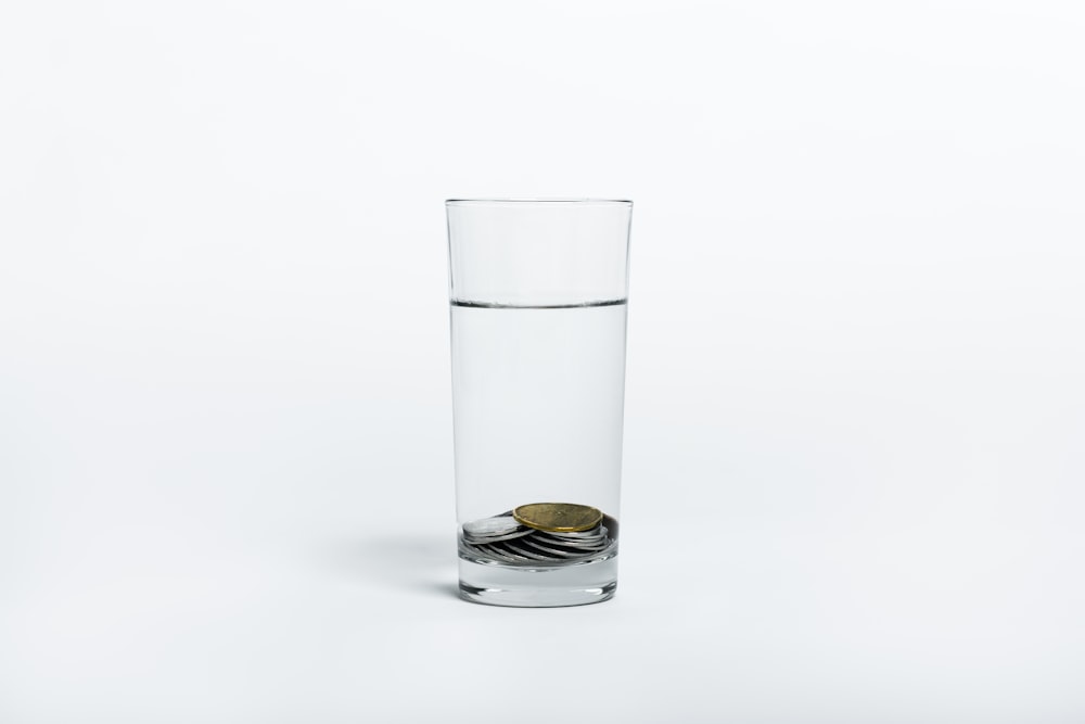 pièces de monnaie sur verre à boire transparent avec de l’eau