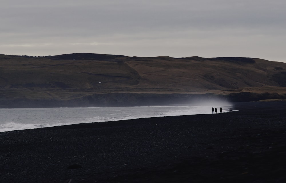 three persons in seashore at daytime